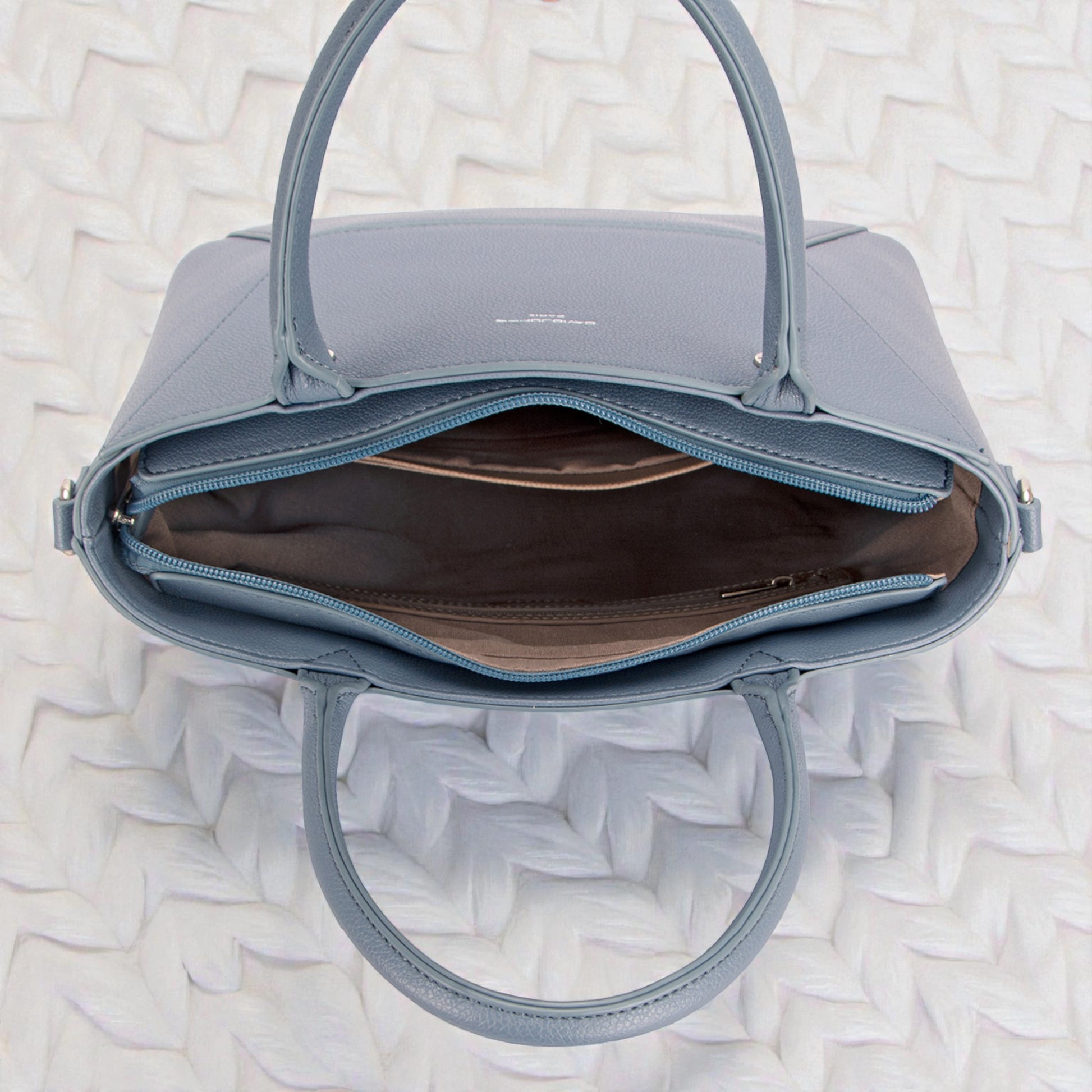 Blue handbag with open top on a textured white background