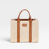 Woven tote bag with brown straps and handle on a light gray background