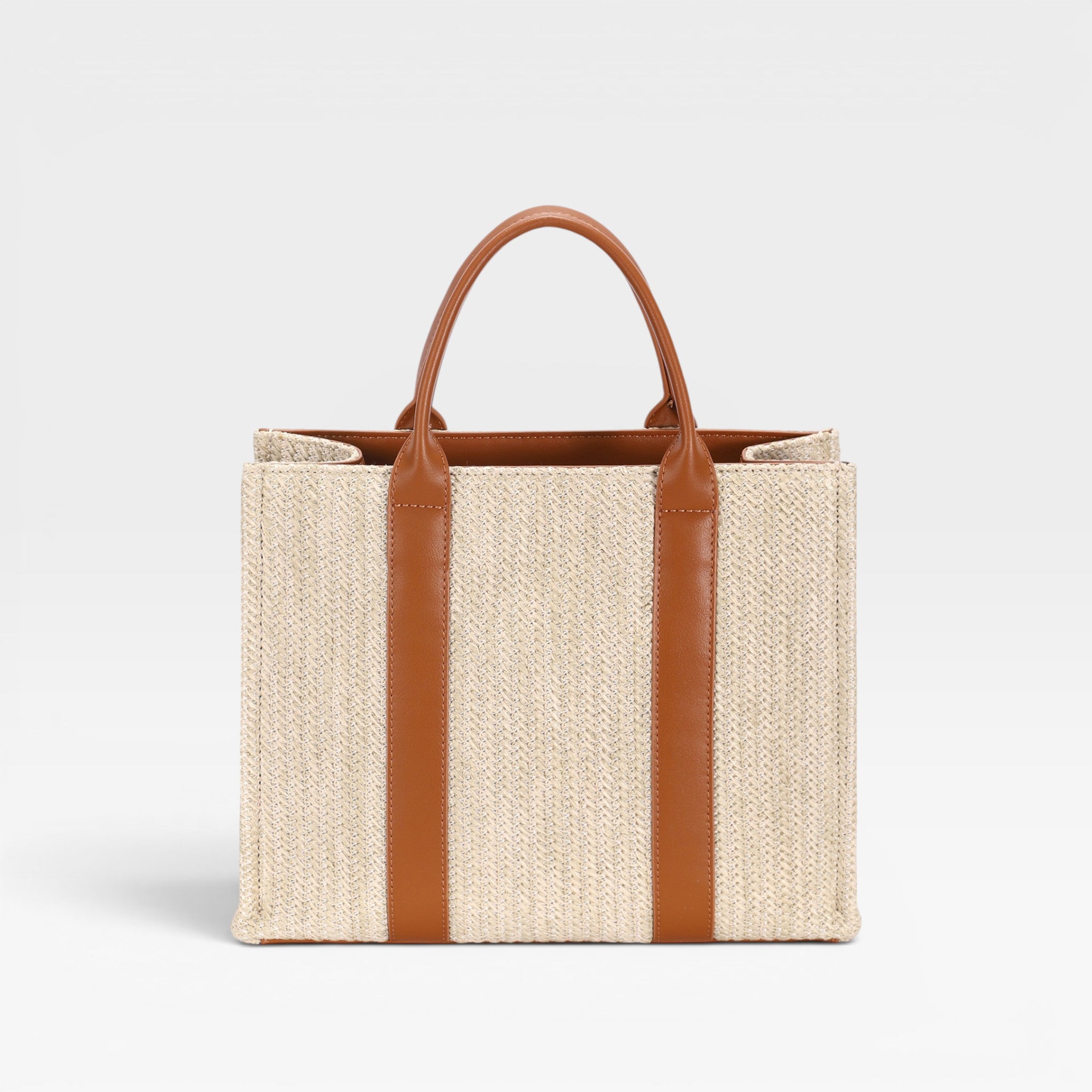 Beige straw tote bag with brown leather straps on a light gray background