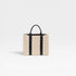 Beige tote bag with black straps on a light gray background