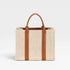 Beige straw tote bag with brown leather straps on a light gray background