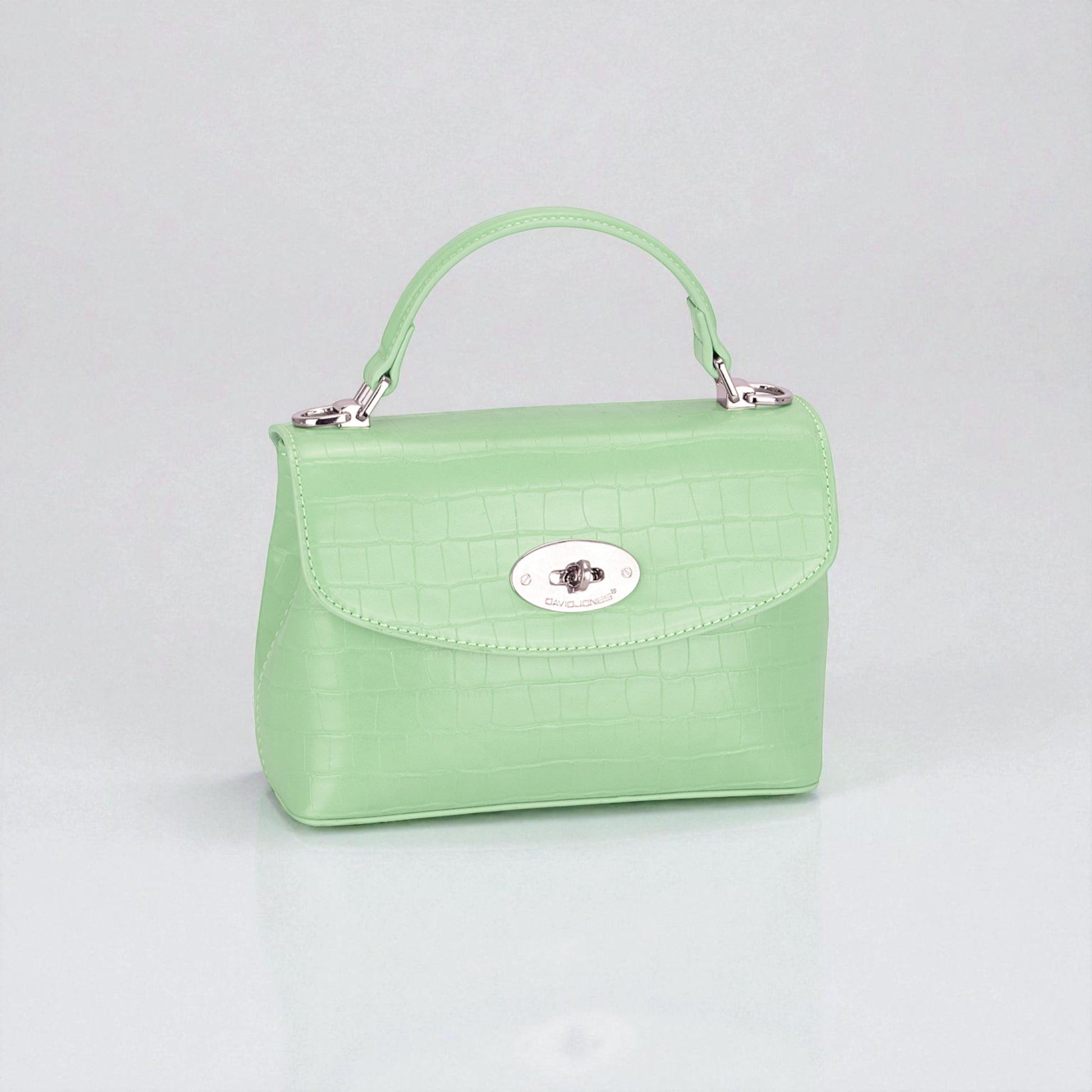 Green handbag with a silver clasp on a light gray background
