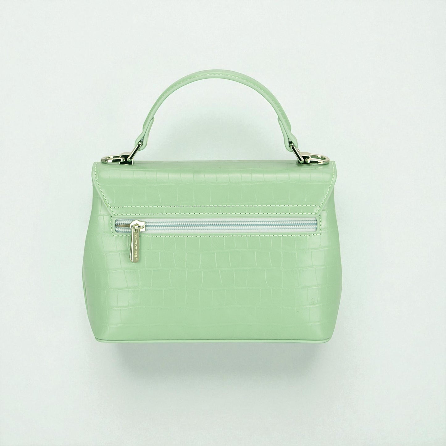 Mint green handbag with a silver zipper on a light gray background