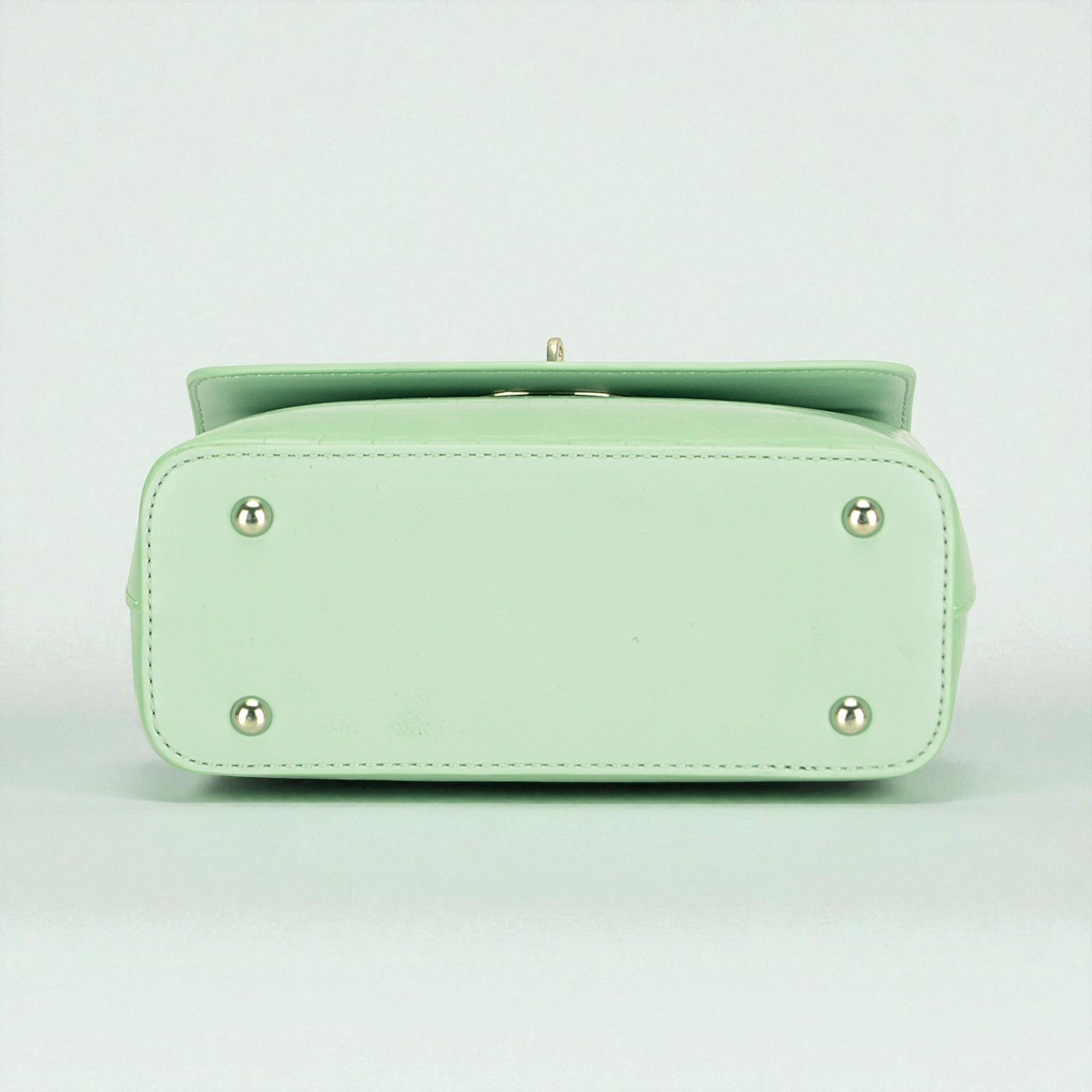 Light green handbag with silver accents on a light gray background