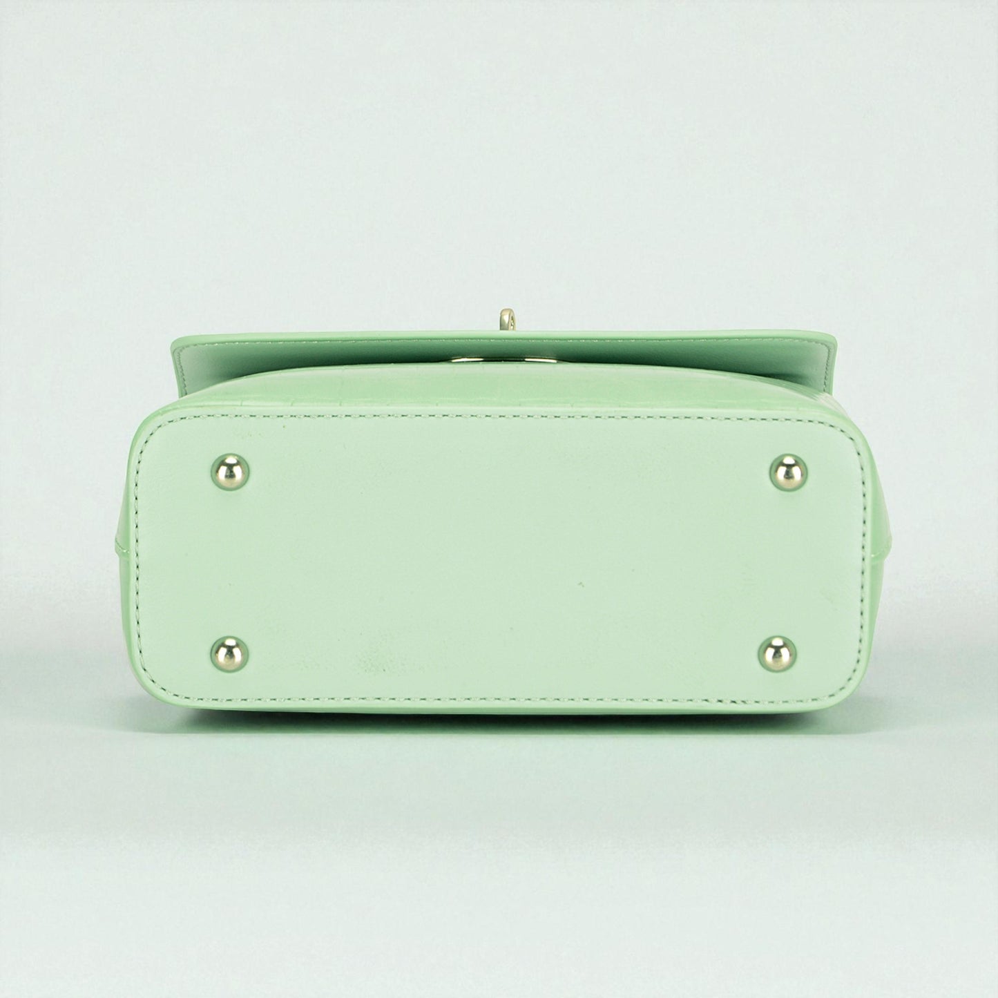 Light green handbag with silver accents on a light gray background
