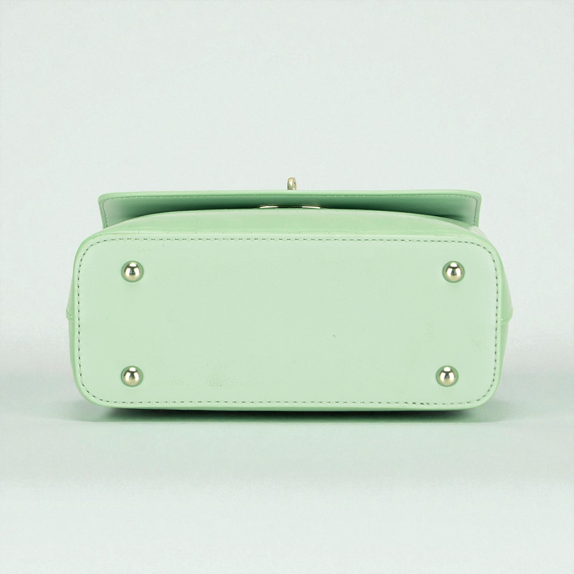 Light green handbag with silver accents on a light gray background