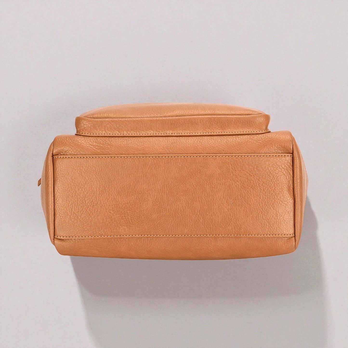 Brown leather toiletry bag on a light gray background