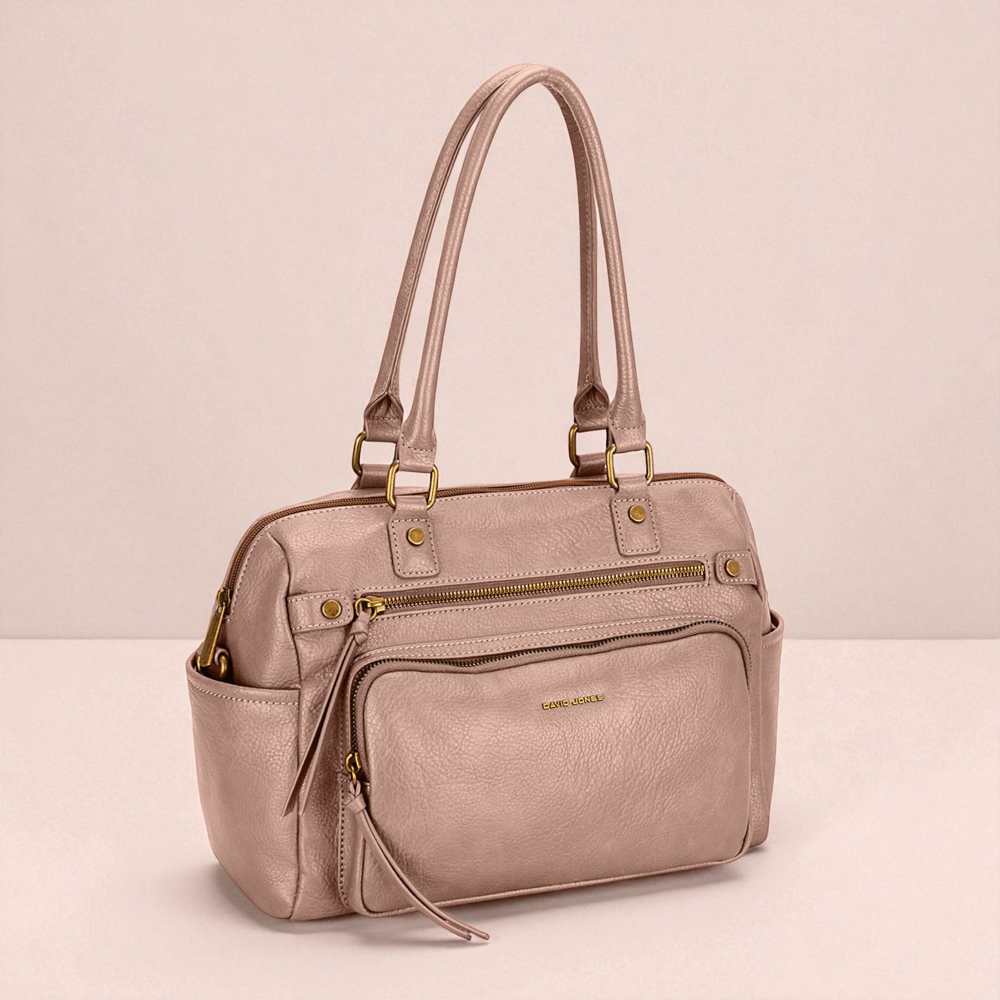 Pink handbag with gold zippers on a light pink background