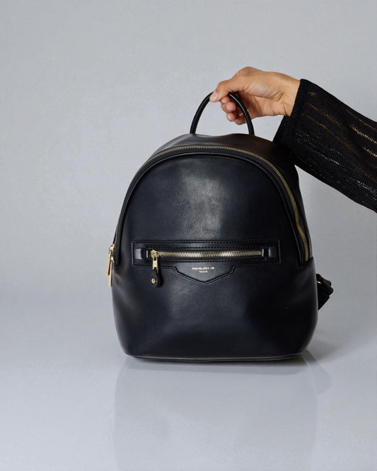 Black leather backpack held by a hand on a light gray background