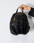 Black backpack held by a hand on a white background