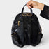 Black backpack held by a hand on a light gray background