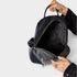 Black backpack being held open by a hand on a light gray background