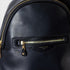 Close-up of a black leather backpack with gold zippers on a light gray background
