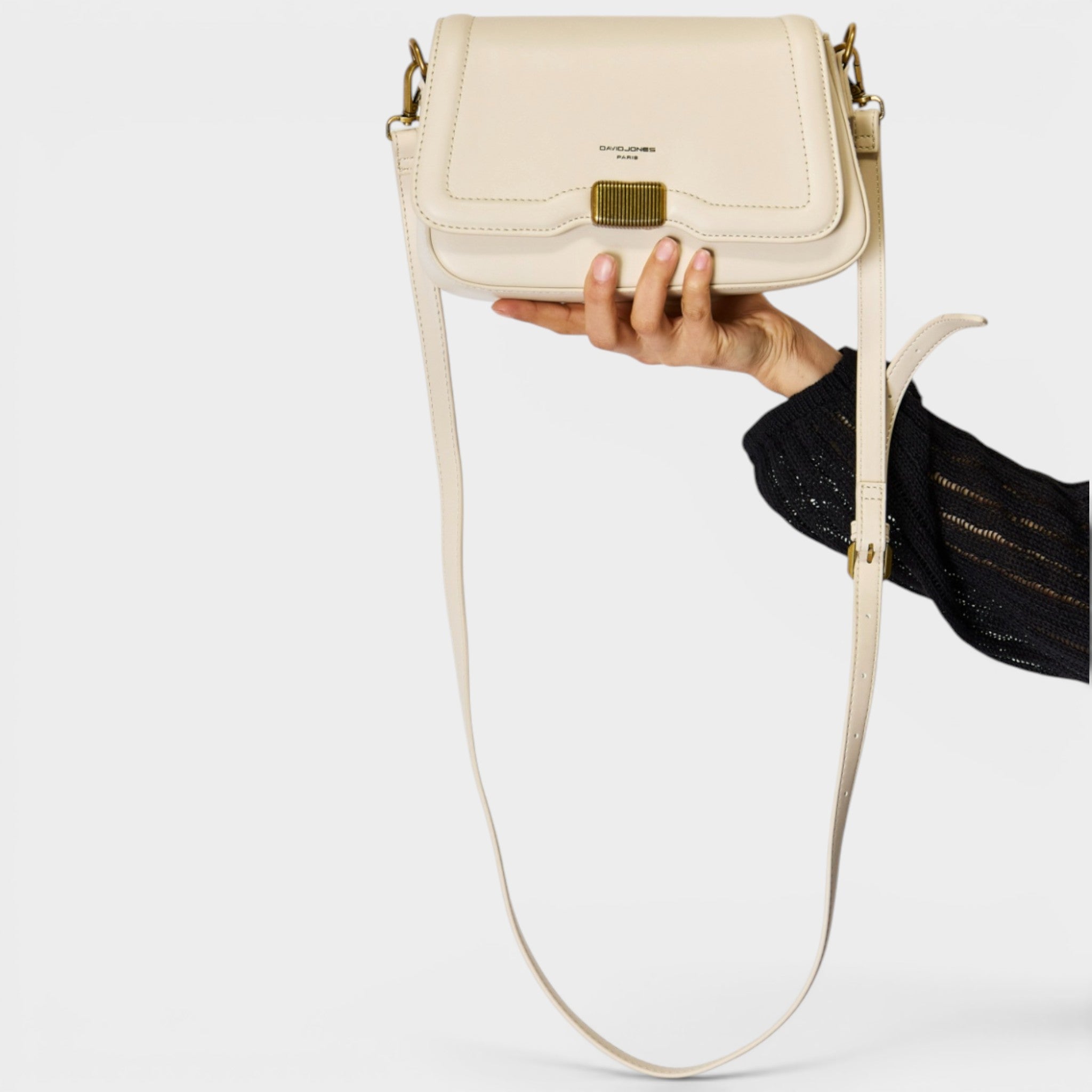 Beige handbag held by a hand on a light gray background