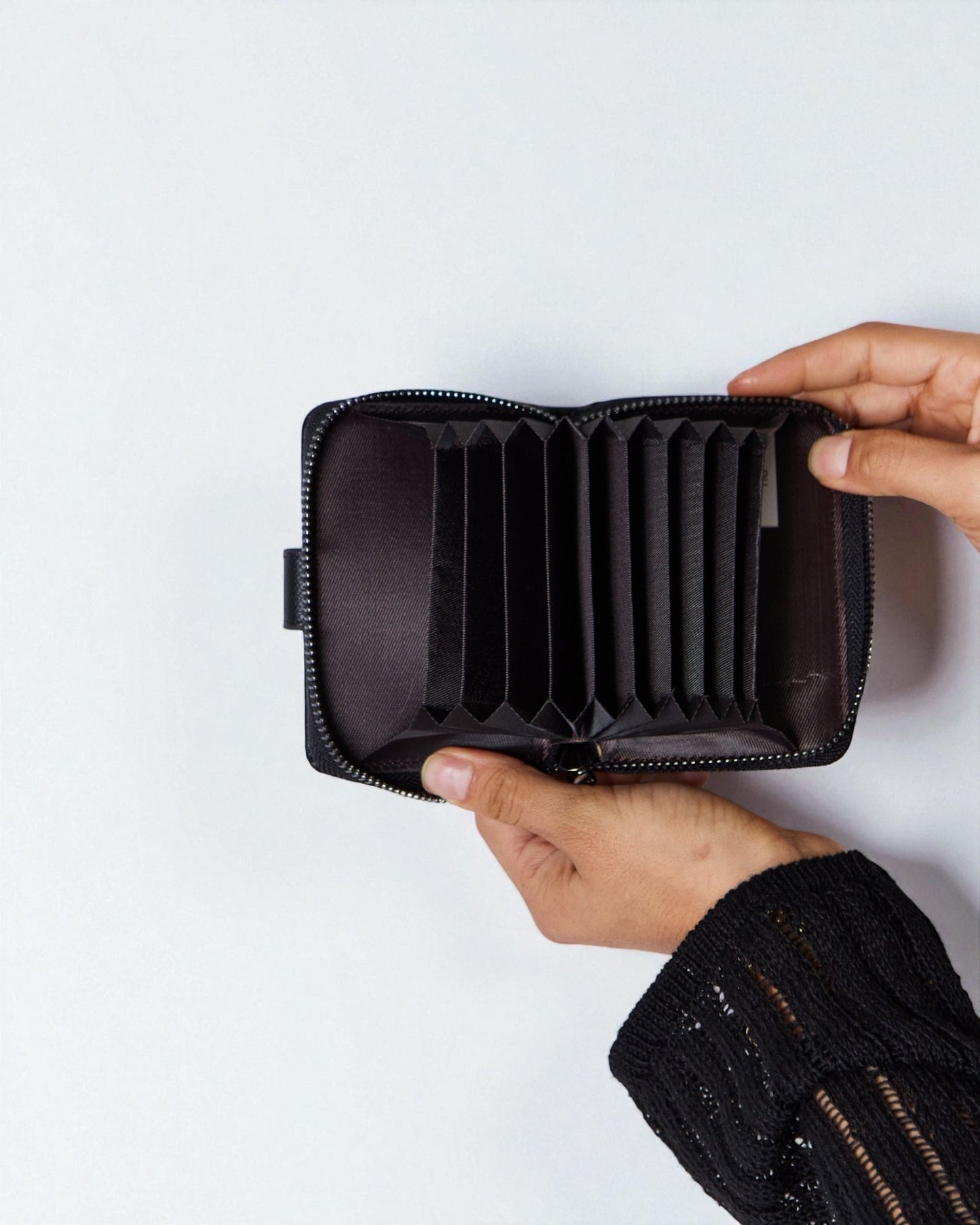 Person holding a black wallet with a white background