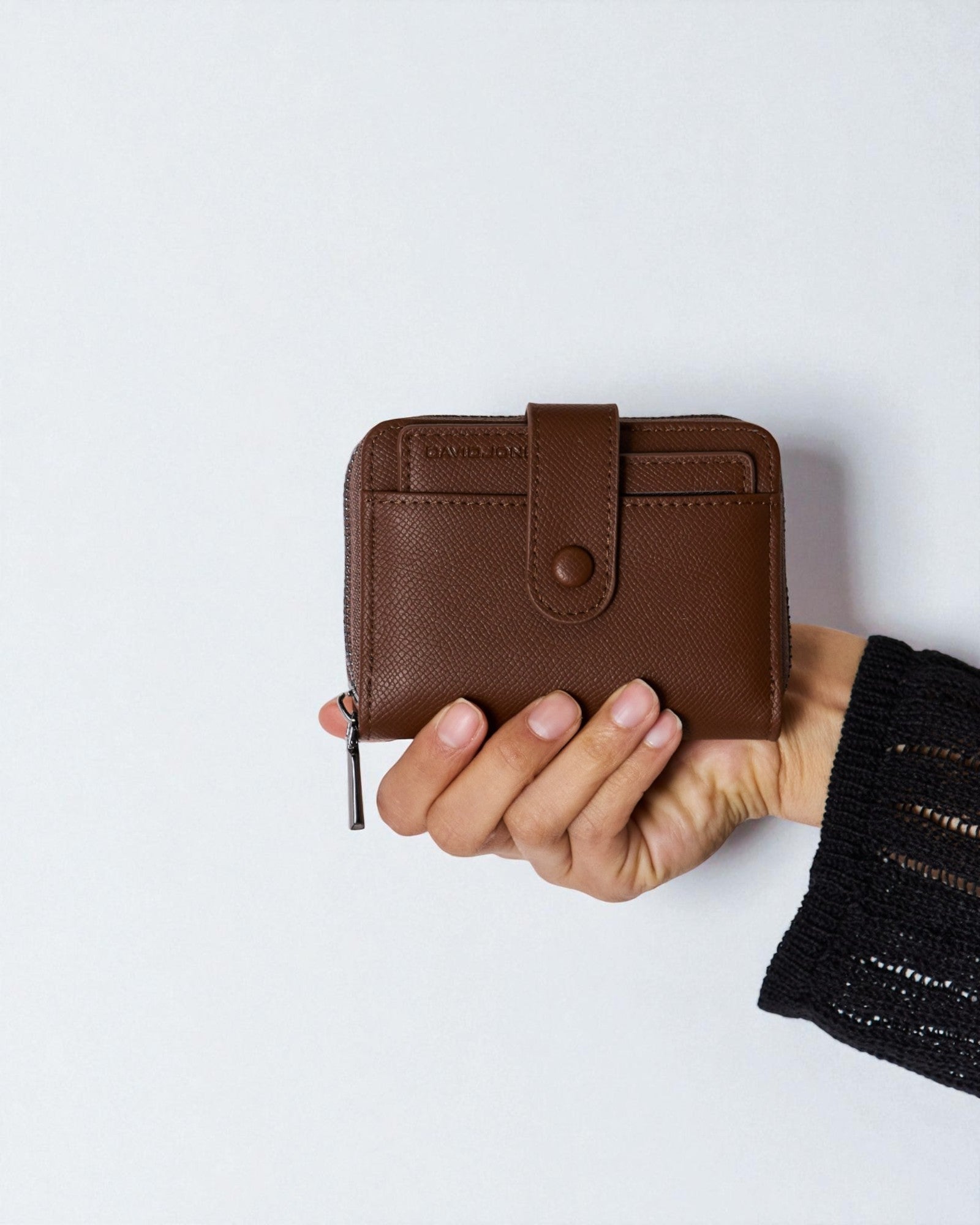 Hand holding a brown wallet against a white background