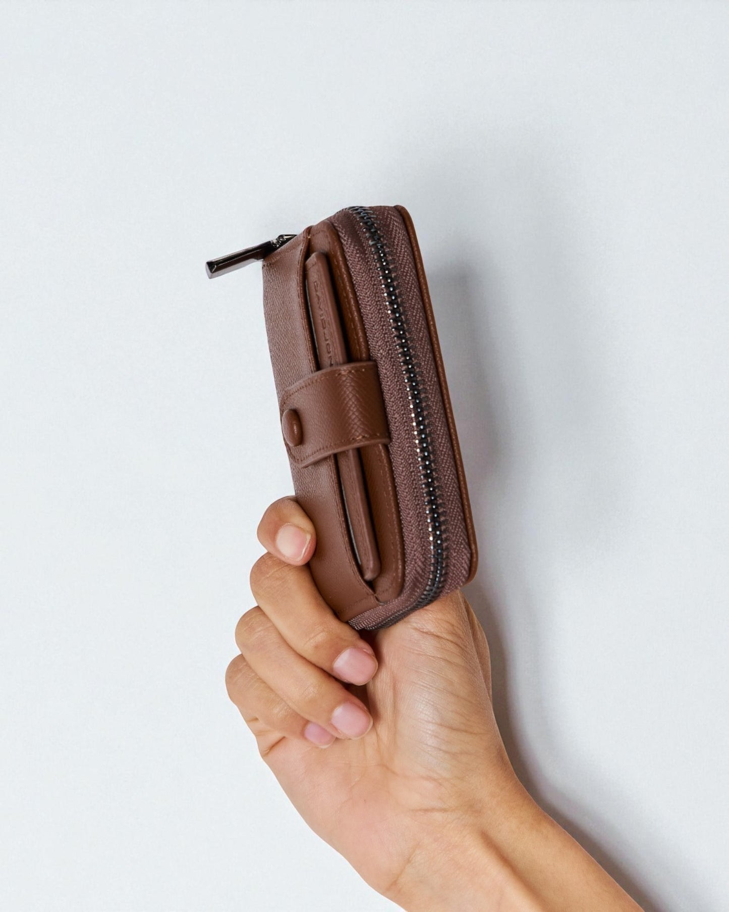 Brown leather wallet held in a hand against a light gray background