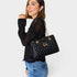 Woman holding a black quilted handbag against a white background
