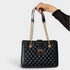 Black quilted handbag with gold chain strap held by a hand on a white background