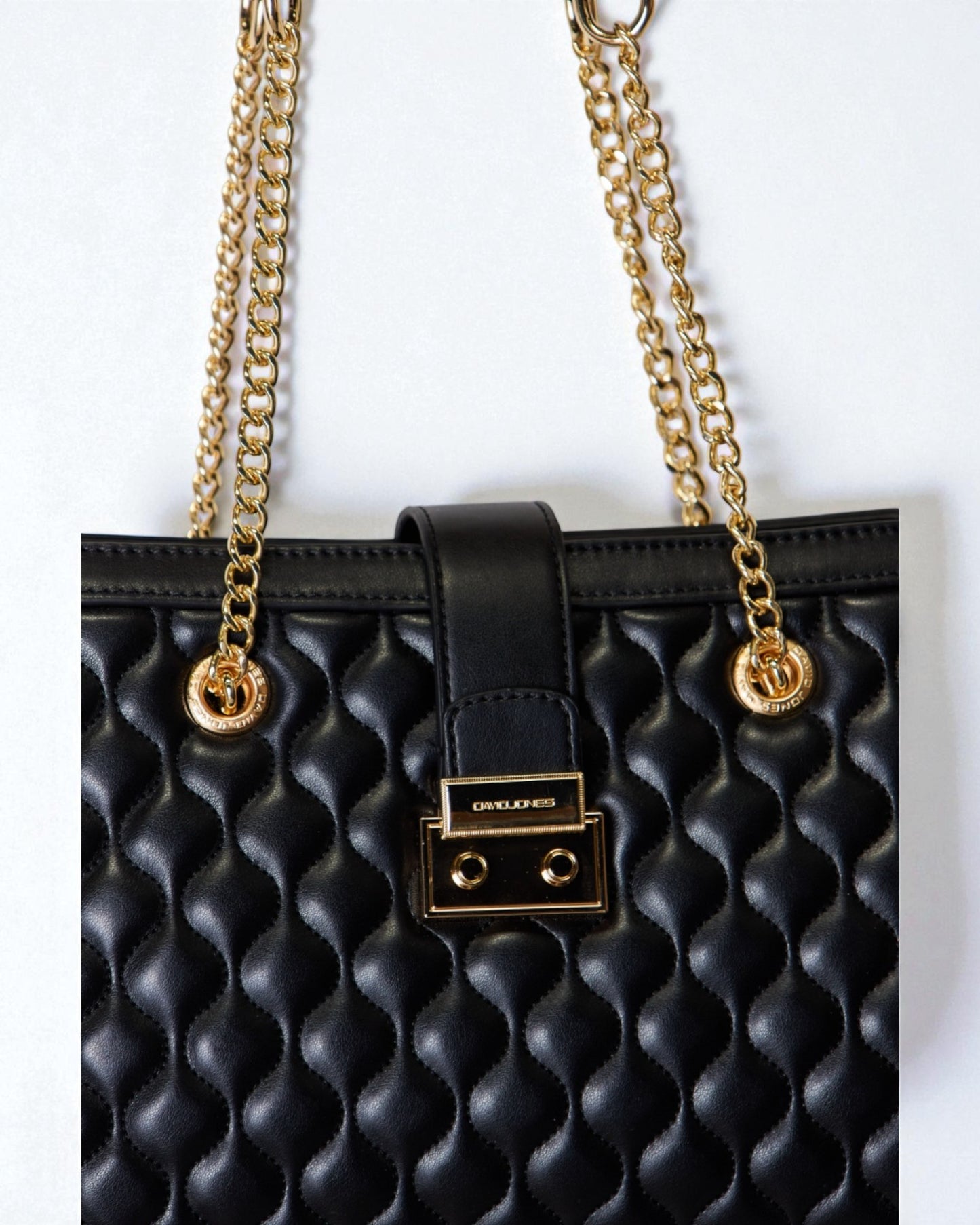 Black textured handbag with gold chain strap on a white background
