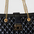 Black quilted handbag with gold chain and clasp on a light gray background