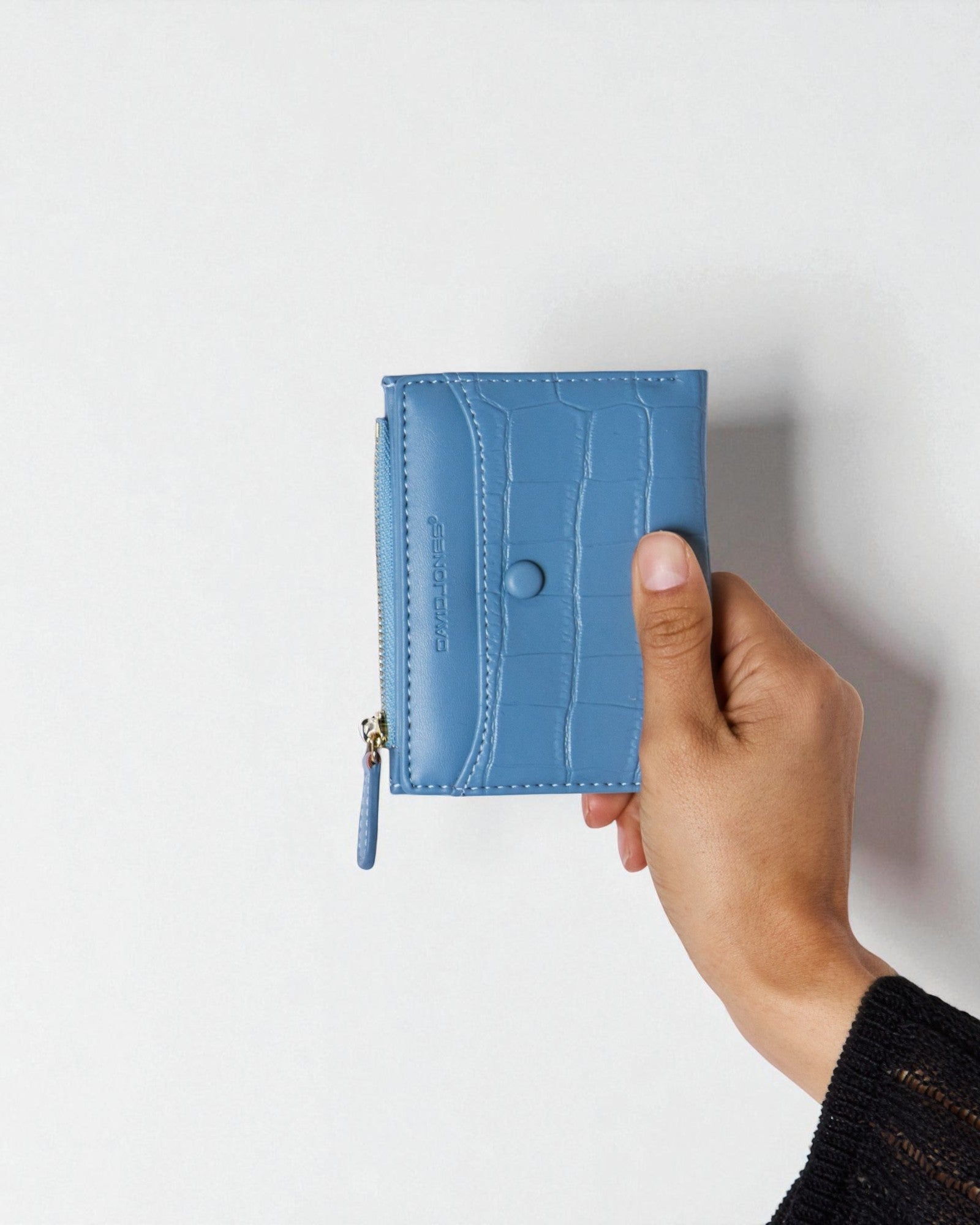 Hand holding a blue wallet against a white background