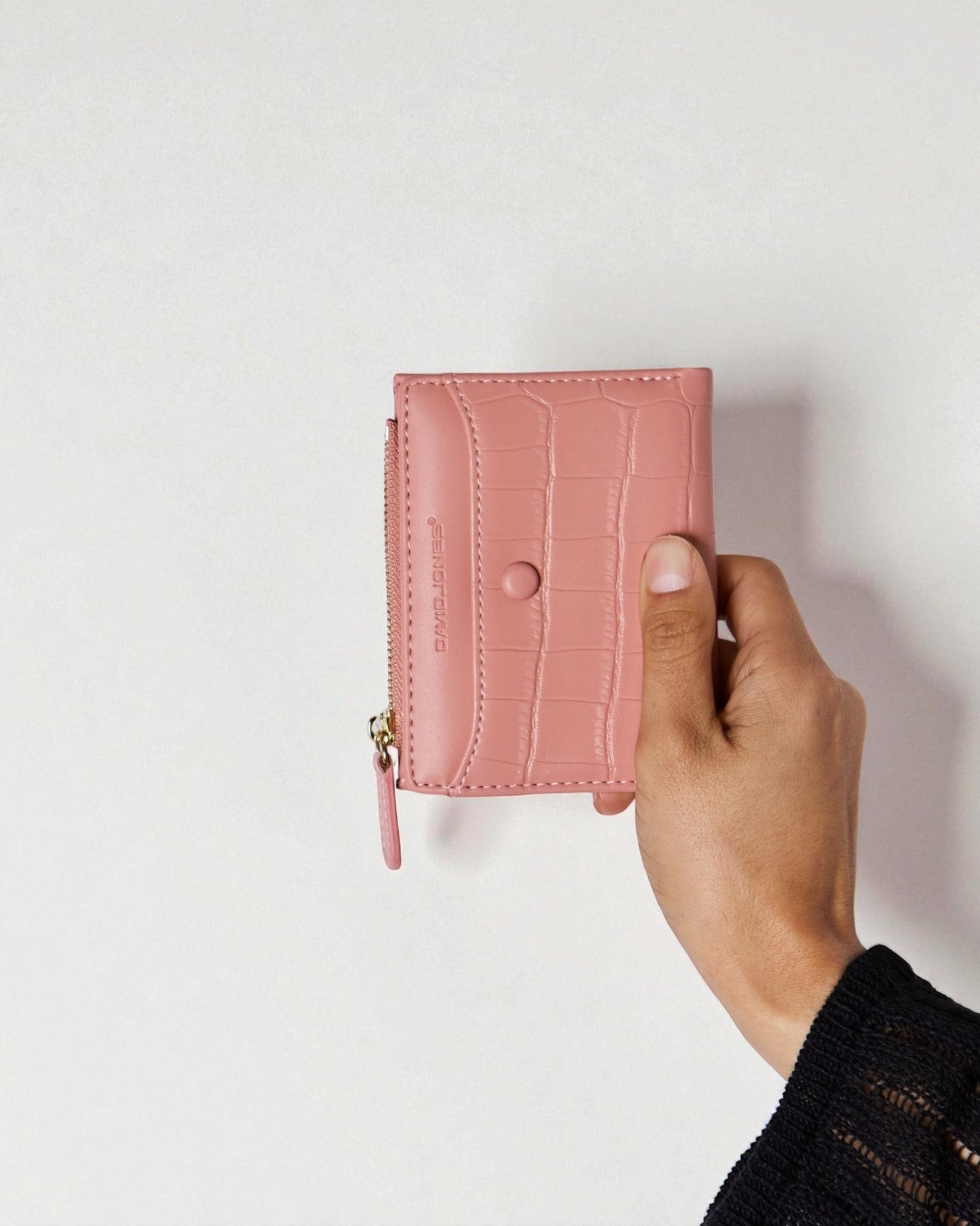 Pink wallet held by a hand against a light background