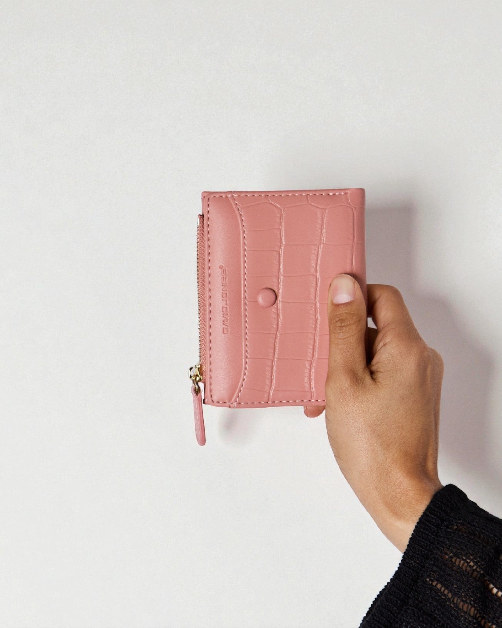 Pink wallet held by a hand against a light background