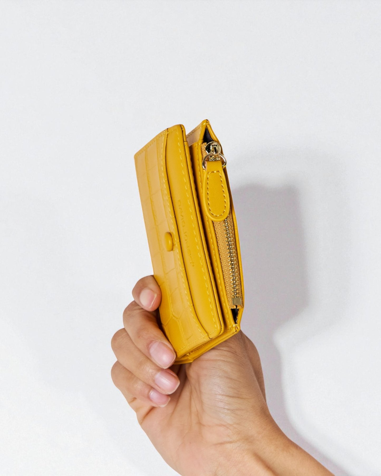 Hand holding a yellow wallet against a white background