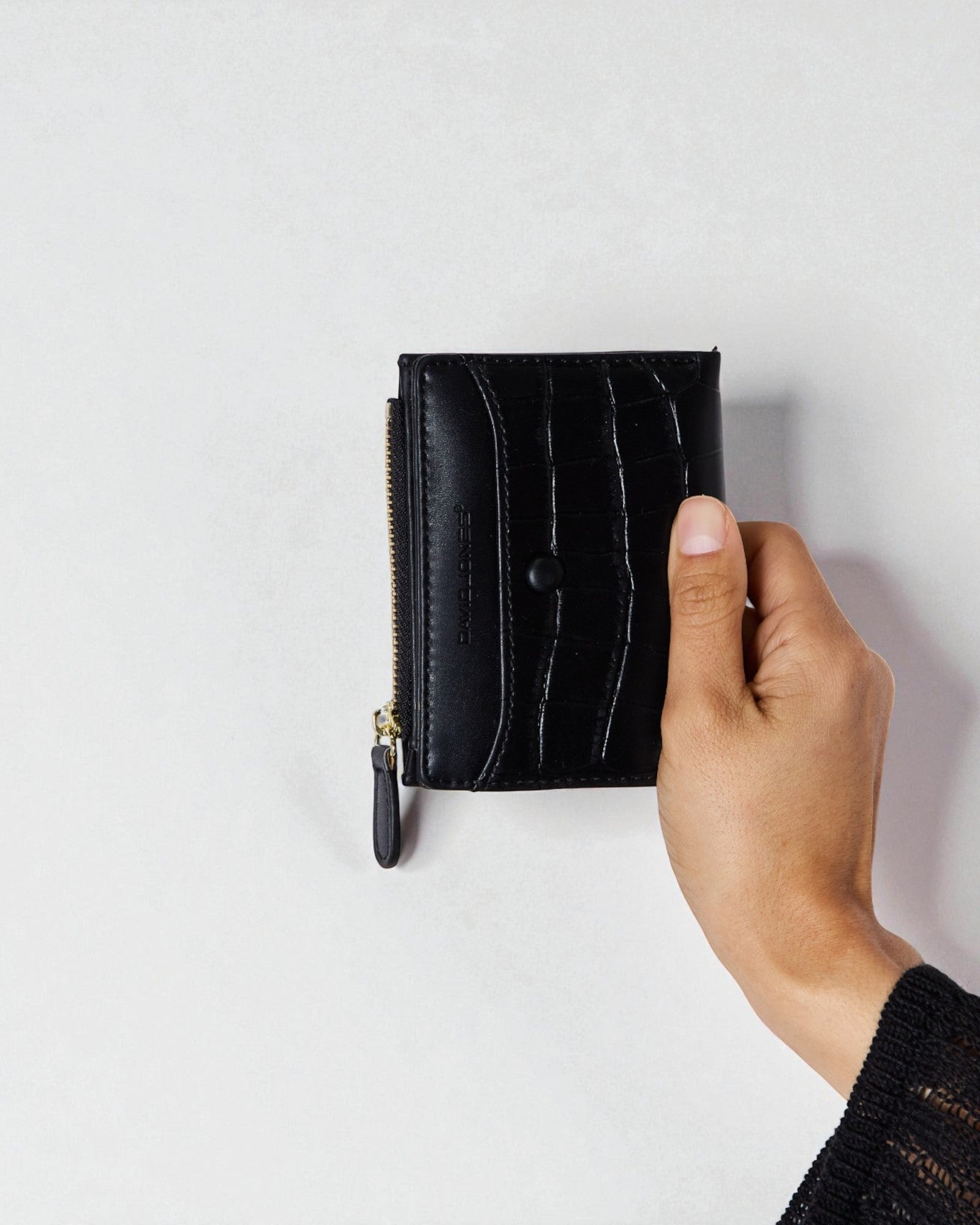 Hand holding a black leather wallet against a light gray background