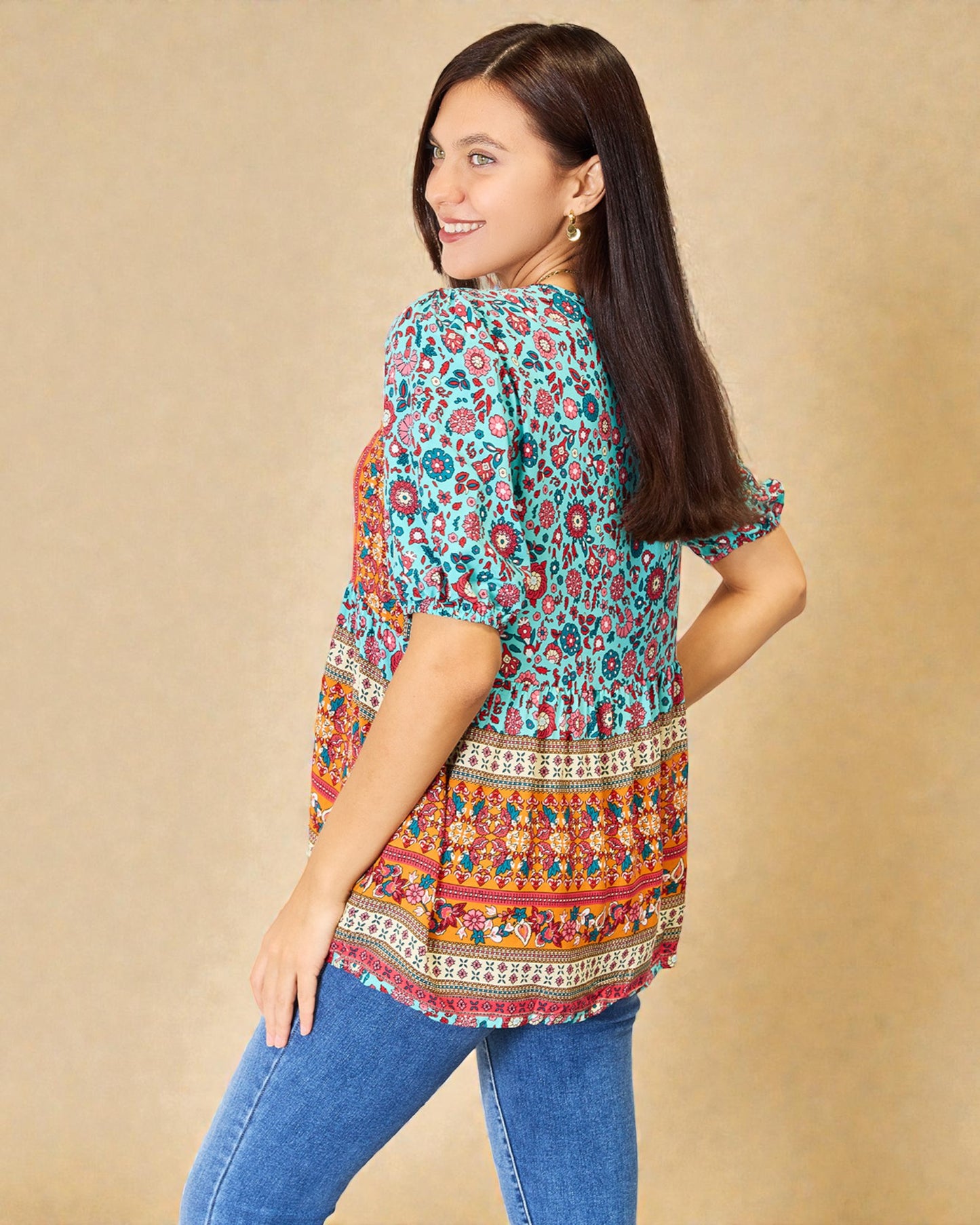 Woman wearing a colorful patterned blouse with a beige background