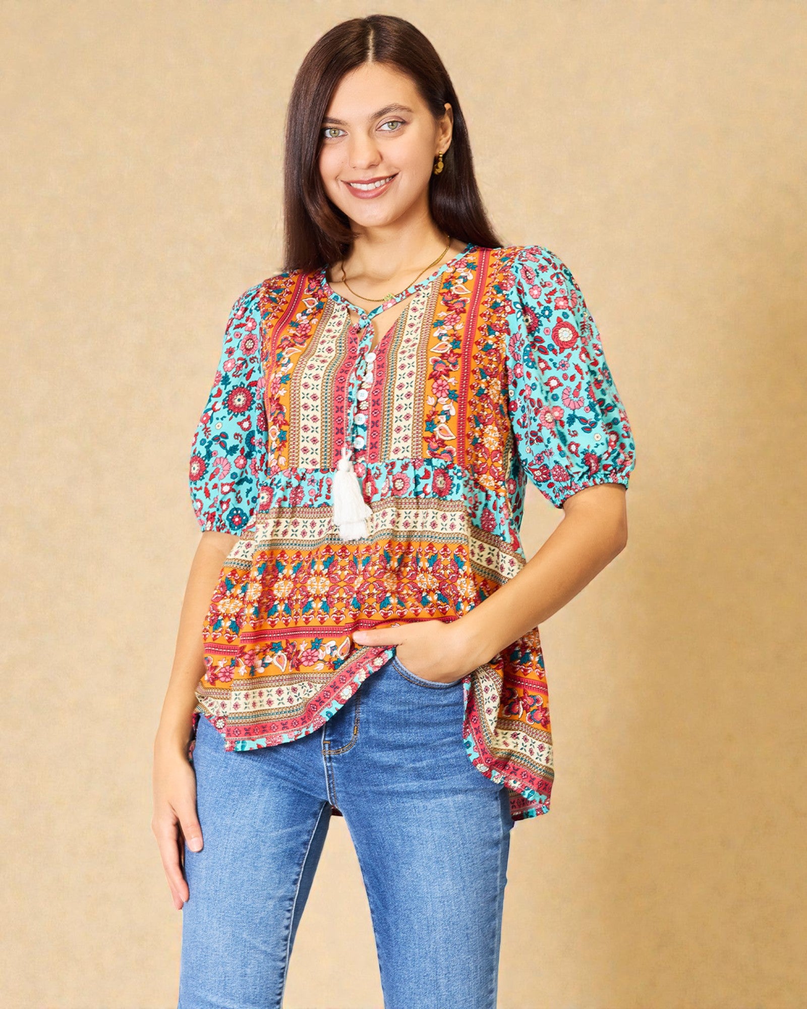 Woman wearing a colorful patterned top and blue jeans against a beige background