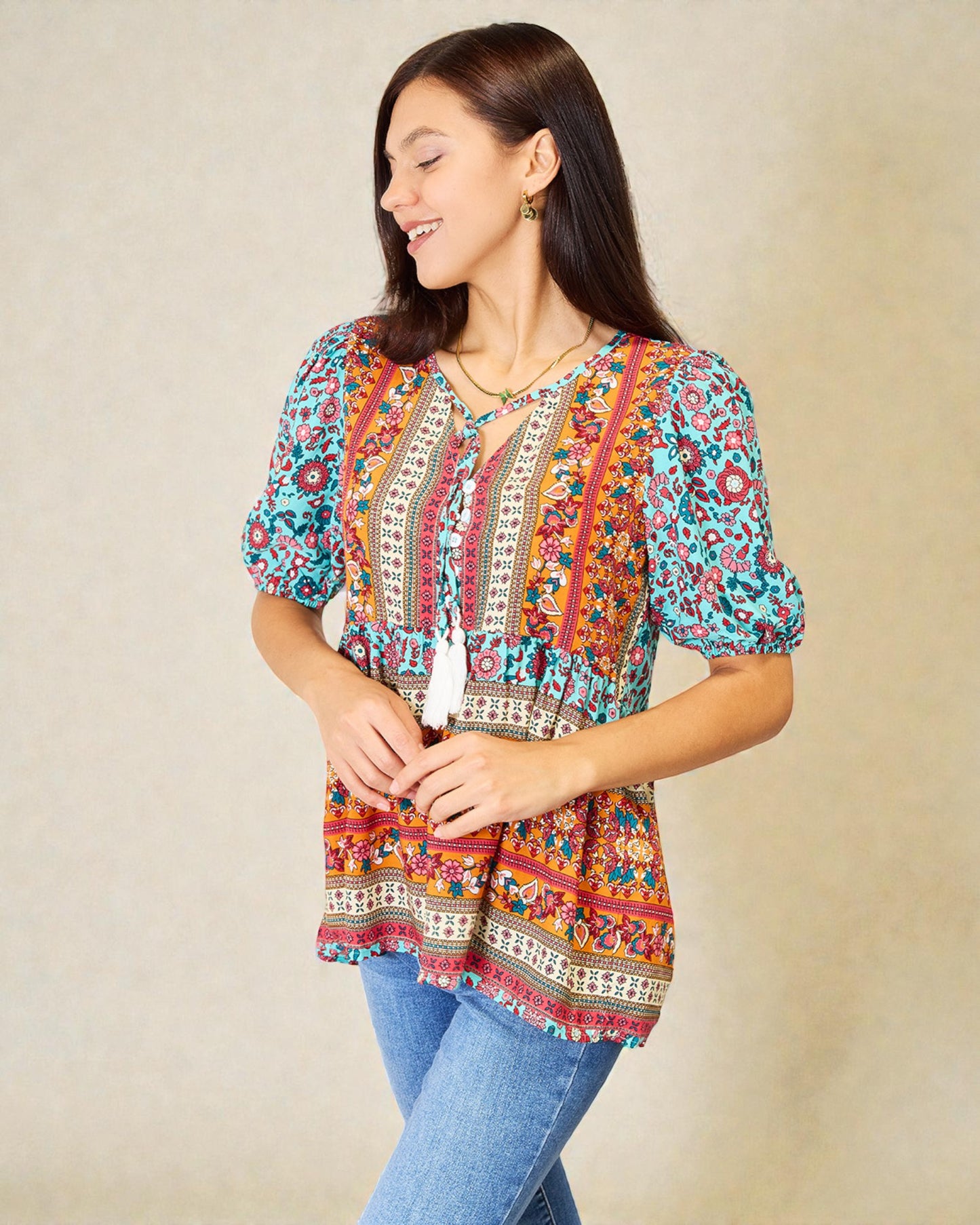Woman wearing a colorful patterned blouse against a beige background
