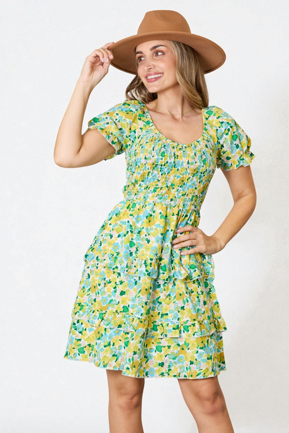 Woman wearing a floral dress and brown hat against a white background