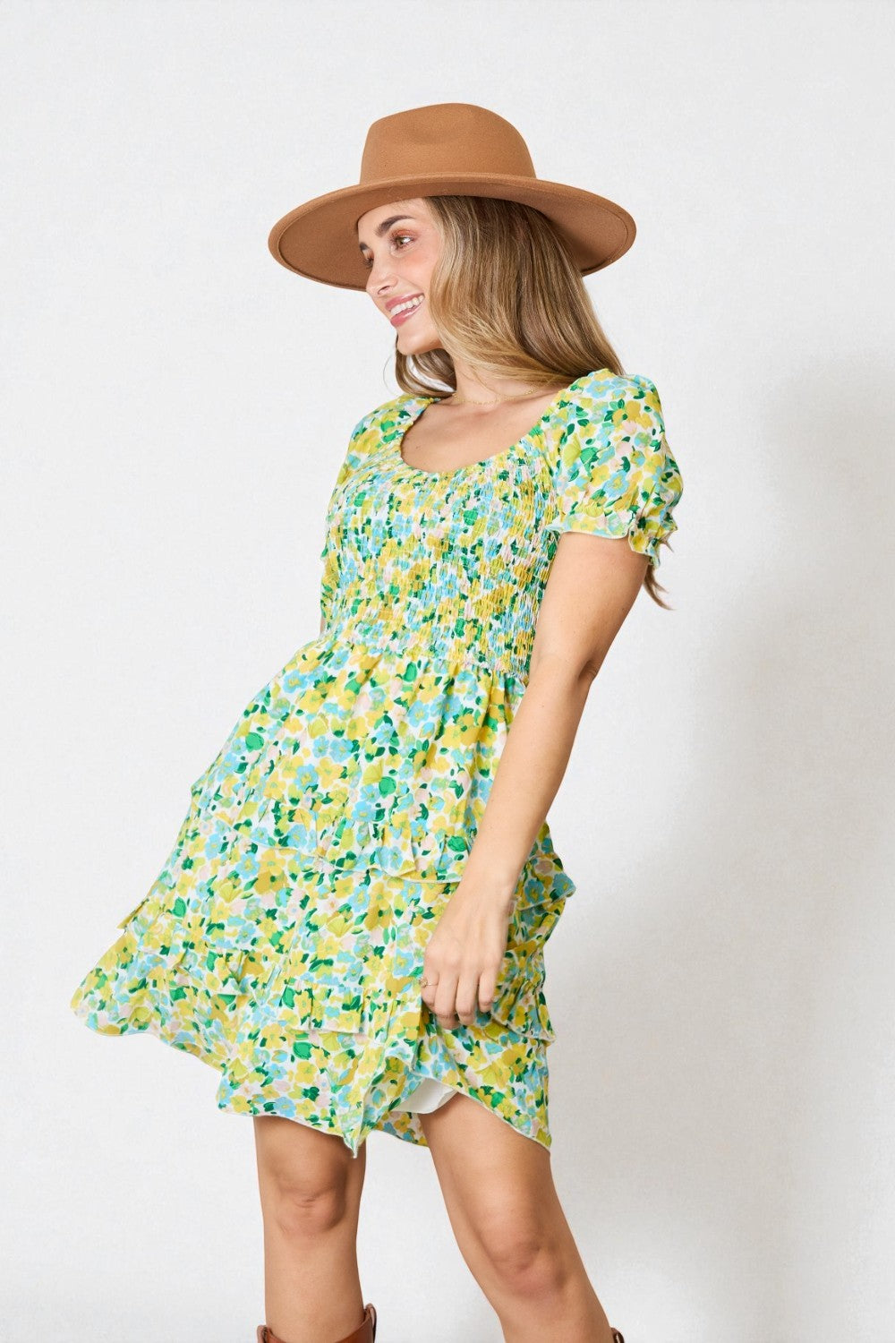 Woman wearing a floral dress and brown hat against a white background