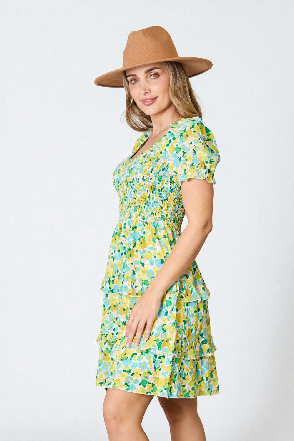 Woman wearing a floral dress and brown hat on a white background