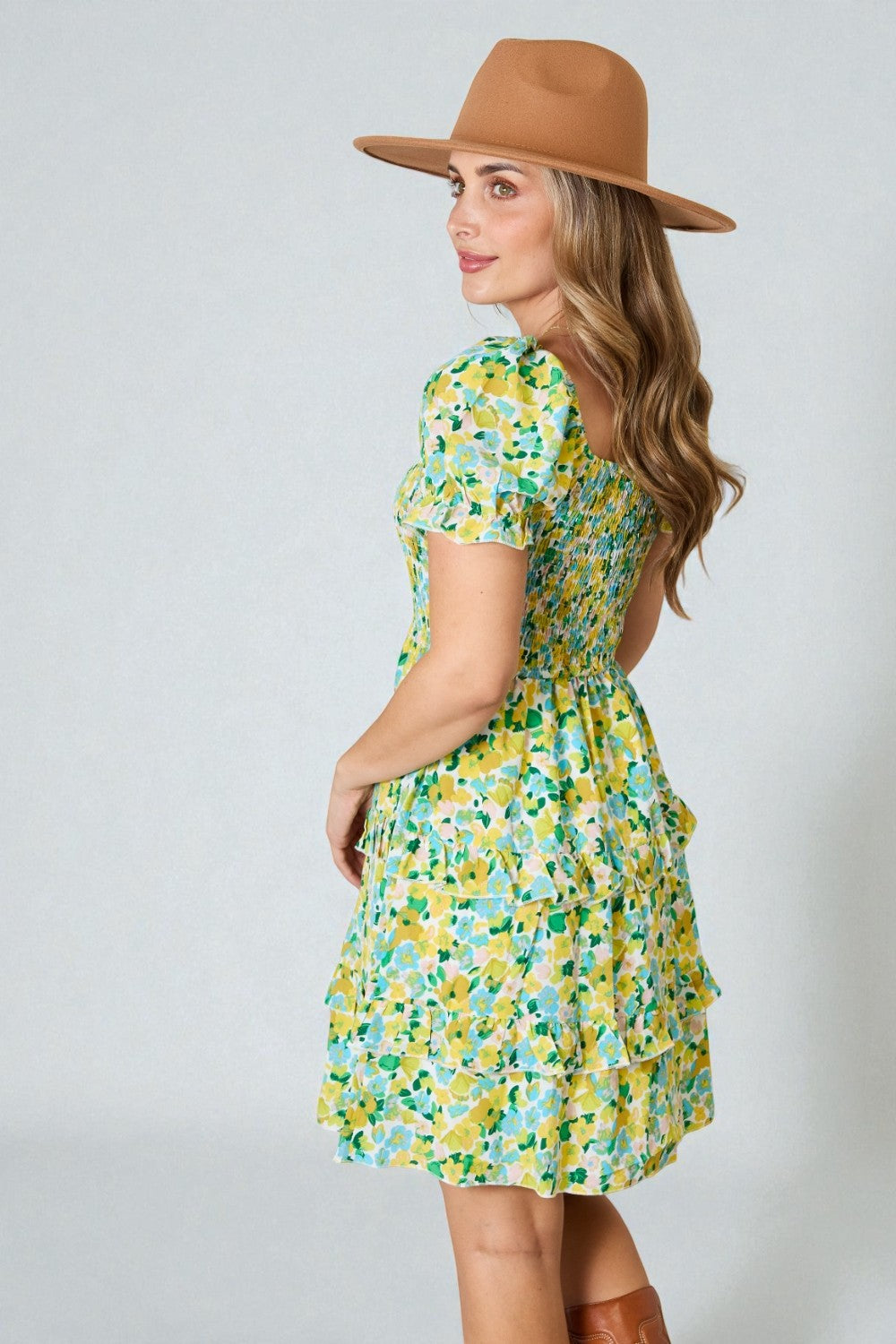 Woman wearing a floral dress and brown hat against a white background