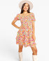 A woman modeling a short-sleeve, tiered mini dress with a vibrant multicolor floral print, styled with a wide-brimmed cream hat and cream boots against a plain white background.