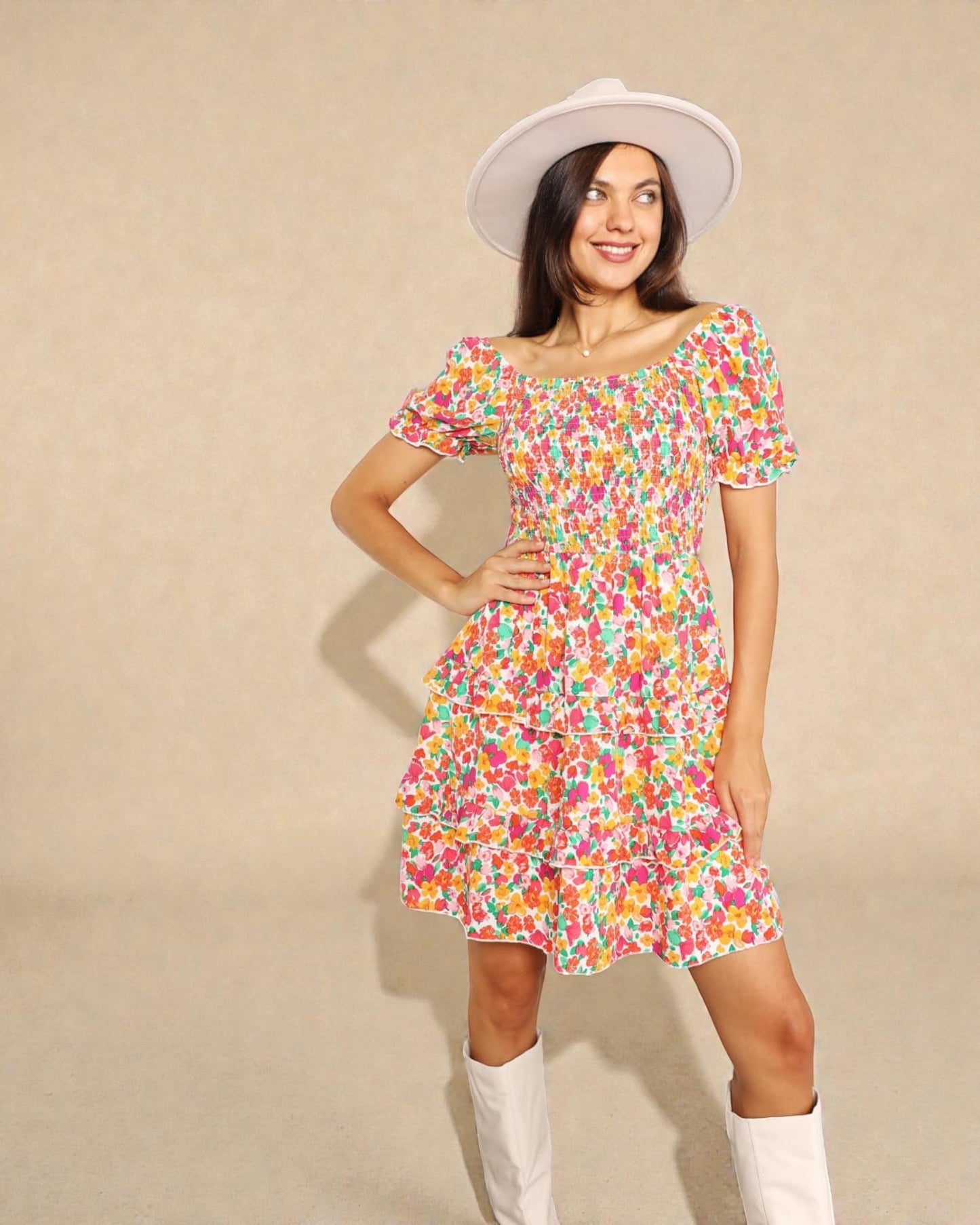 Woman wearing a colorful floral dress and white hat against a beige background