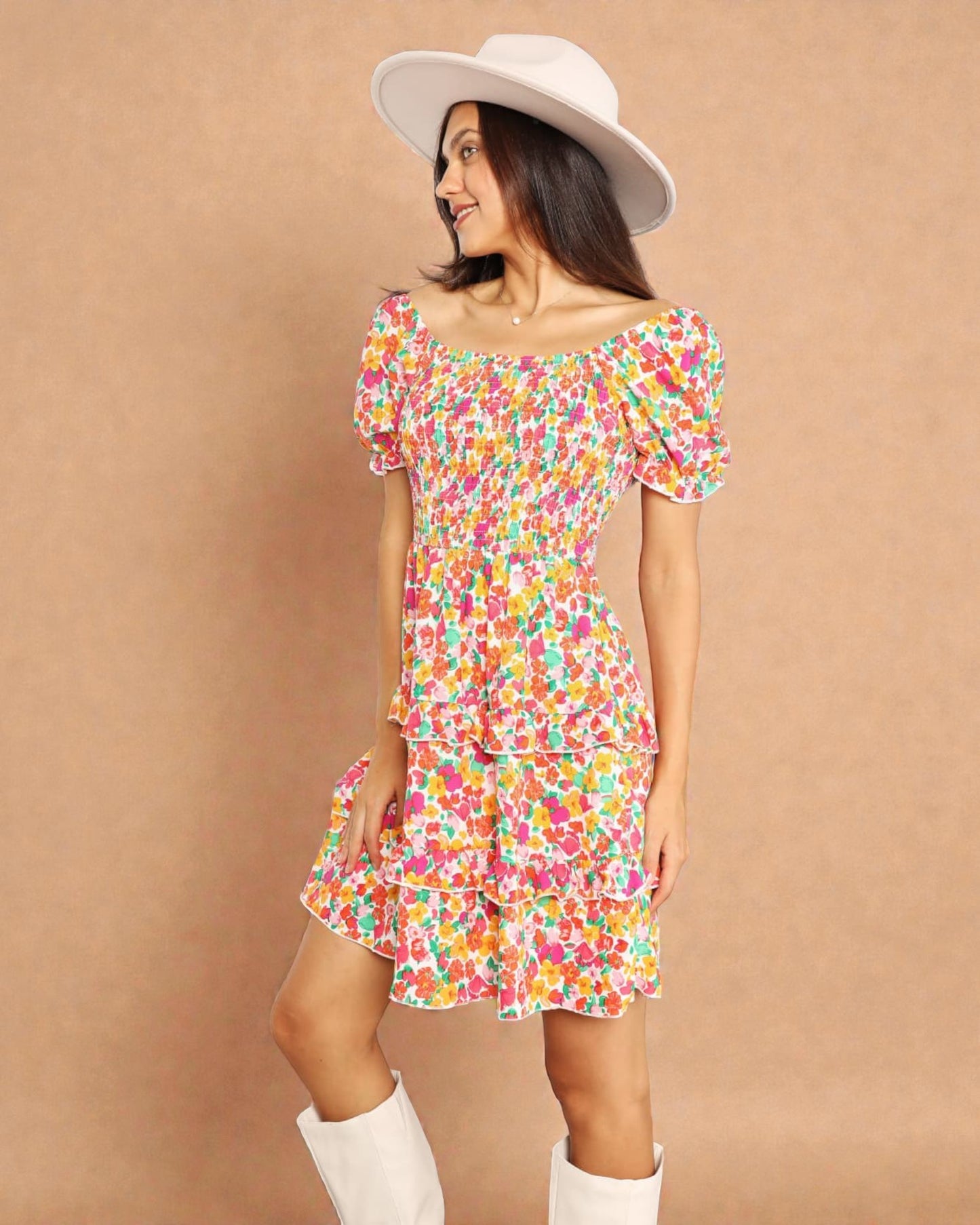 Woman wearing a colorful floral dress and white boots against a brown background