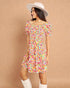 Woman wearing a colorful floral dress and white boots against a brown background