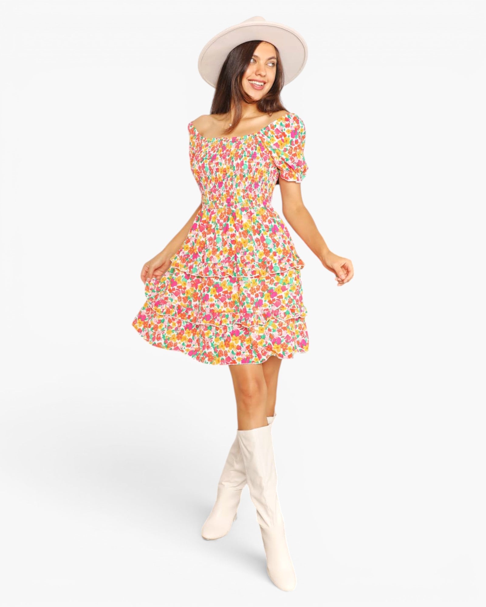 A woman modeling a short puff-sleeve dress with a colorful floral print, paired with a cream wide-brim hat and cream knee-high boots, against a plain white studio background.