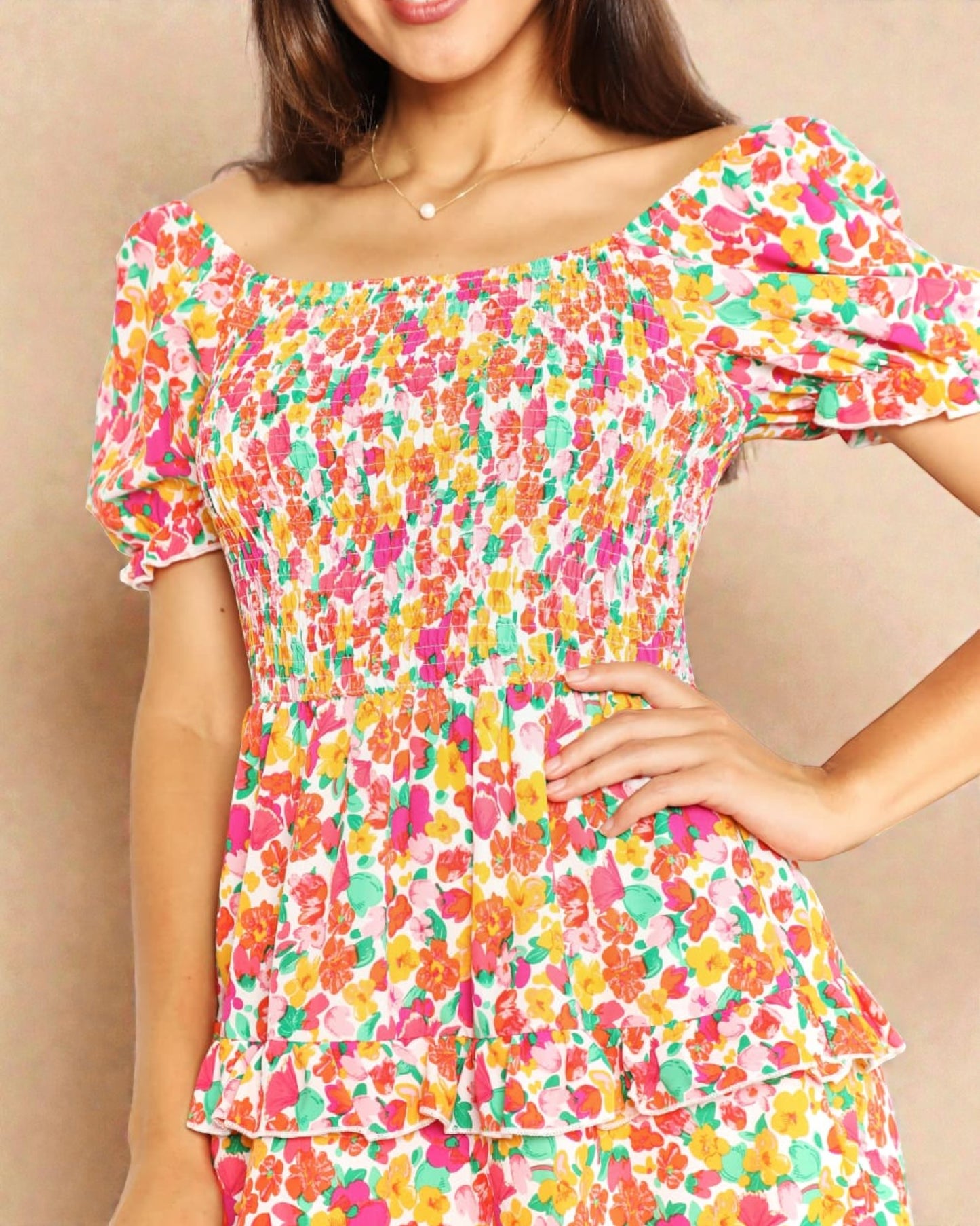 Woman wearing a colorful floral dress against a beige background