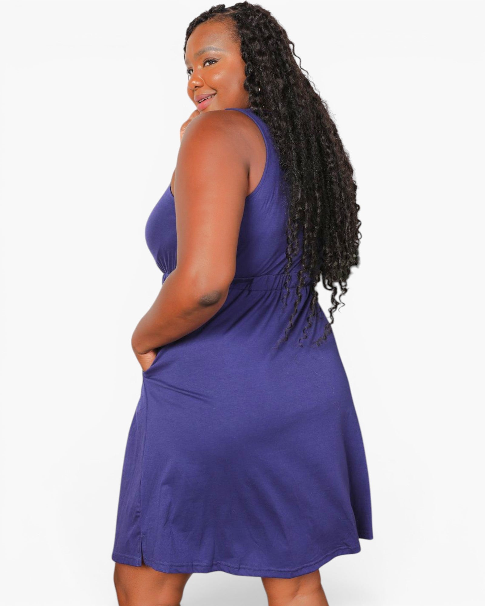 A woman modeling a sleeveless purple A-line dress against a plain white studio background.