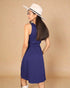 Woman wearing a blue dress and white hat against a beige background