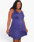 A woman modeling a sleeveless purple A-line dress with a button-down front and a gathered waist, set against a plain white studio background.