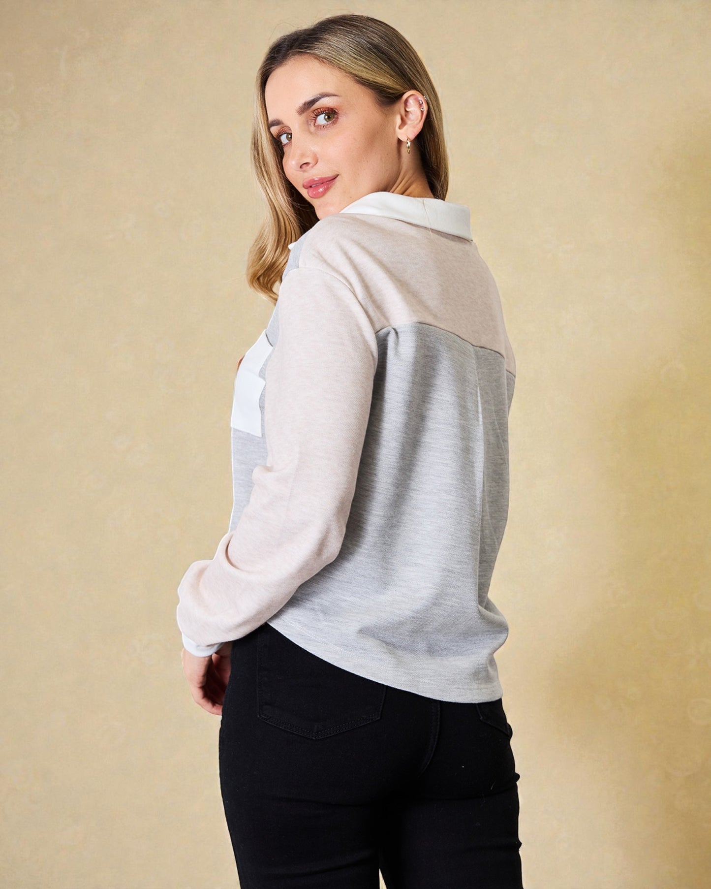 Woman wearing a light gray and white long-sleeve shirt against a beige background