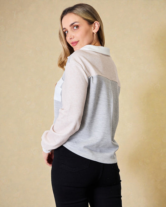 Woman wearing a light gray and white long-sleeve shirt against a beige background