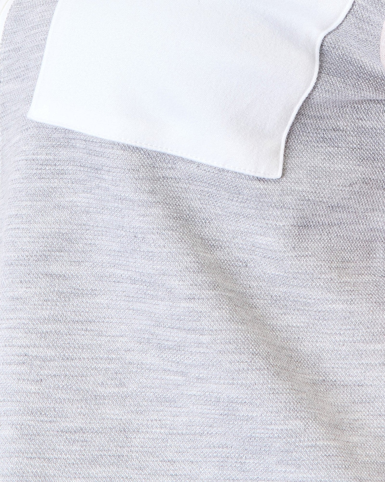 Close-up of a light heather gray knit fabric with a white folded collar or pocket edge visible at the top.