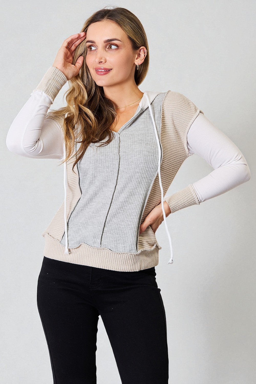 Woman wearing a light gray zip-up vest over a white long-sleeve shirt on a plain background